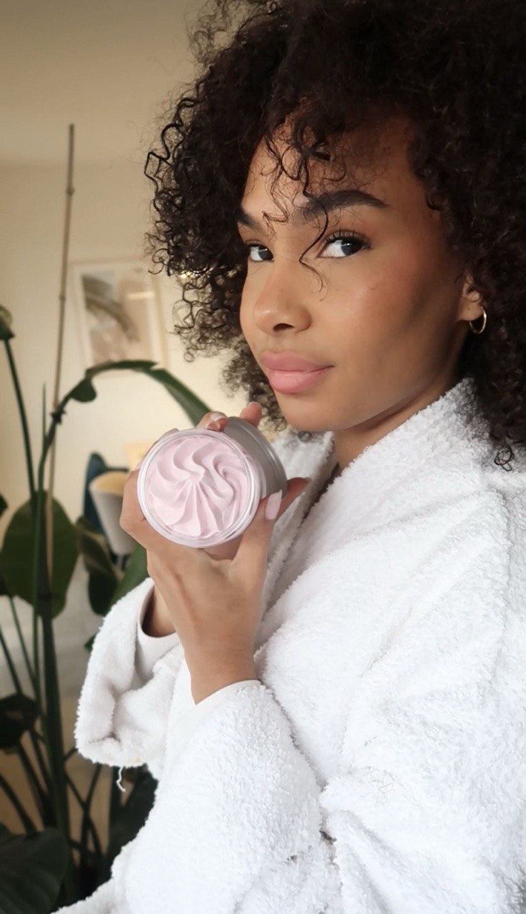 Femme aux cheveux bouclés tenant un pot de chantilly de karité Lianara