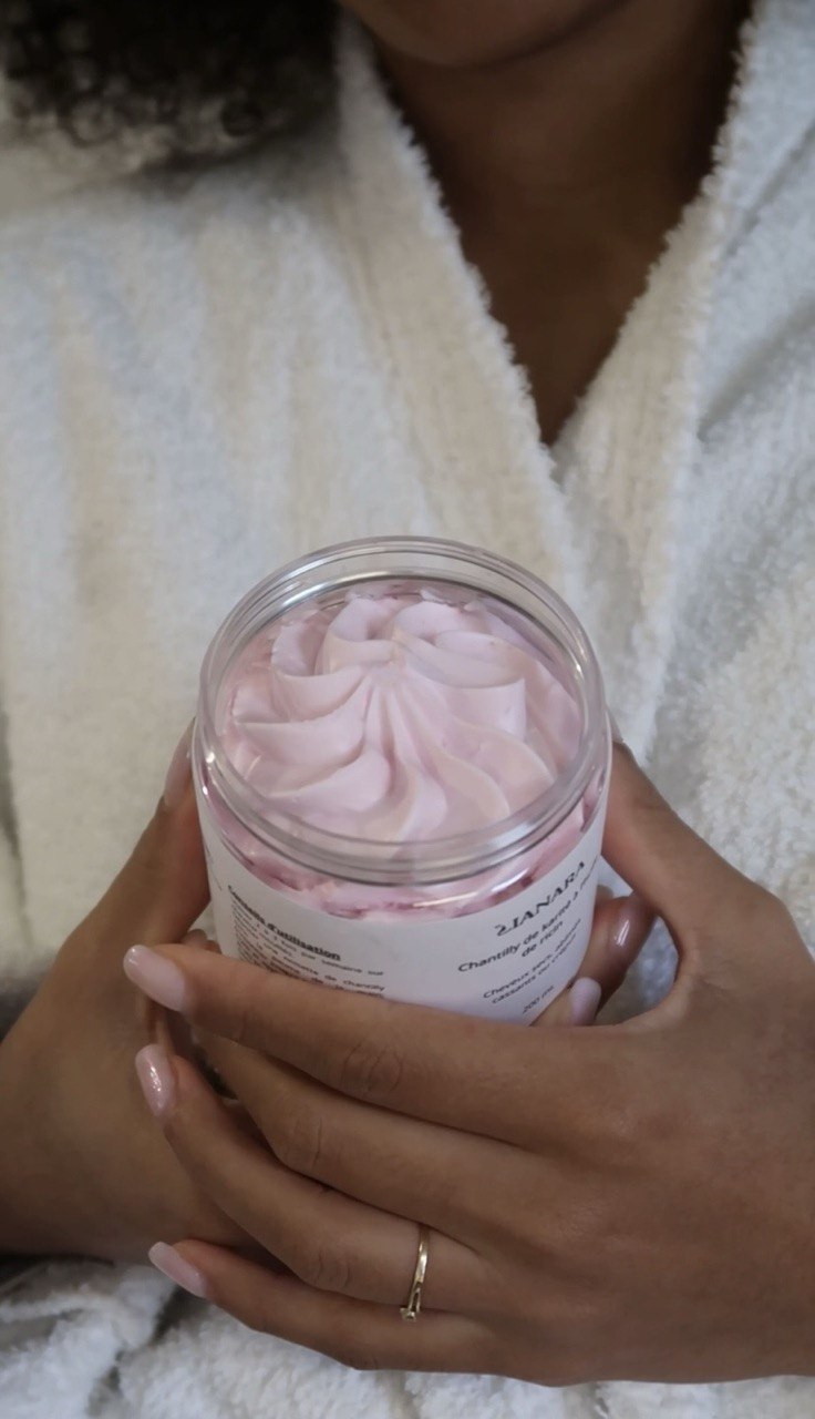Mains tenant un pot de chantilly rose Lianara, soin nourrissant pour cheveux bouclés